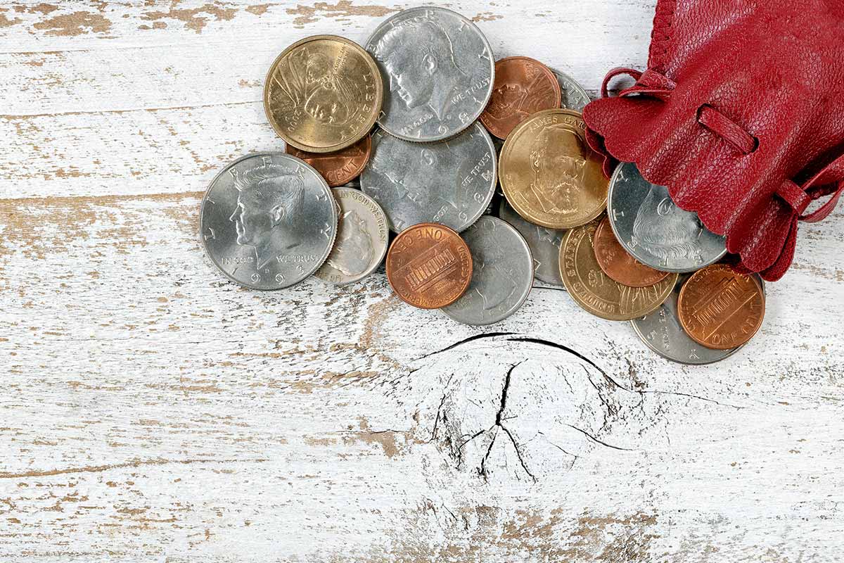 sacchetto di monete in argento e bronzo aperto su tavolo 