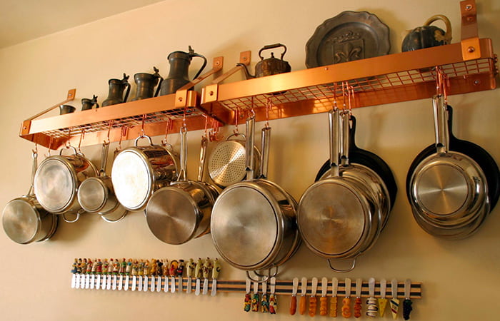 pentole da cucina appese su mensola in rame