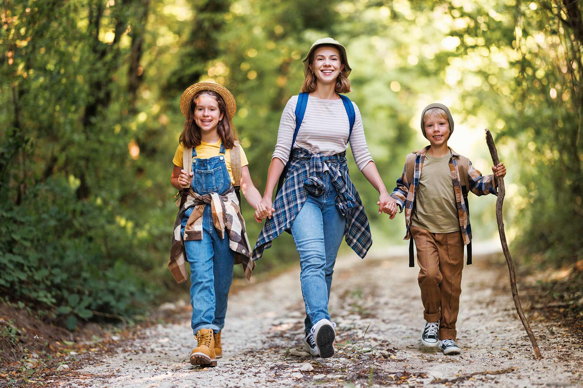 mamma tiene per mano i figli sorridenti in un bosco