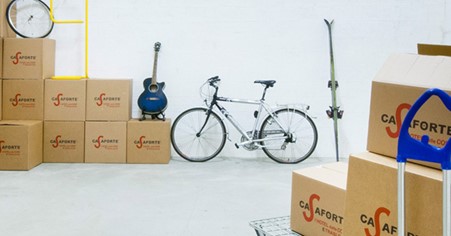 bicicletta chitarra sci e scatoloni dentro un magazzino